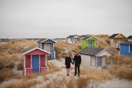 Wedding photographer Malmo - Couple posing in front of colorful wooden huts in Skanor Falsterbo, Sweeden
